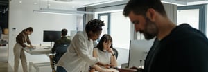 Five employees in an open floor plan office working at different computer stations