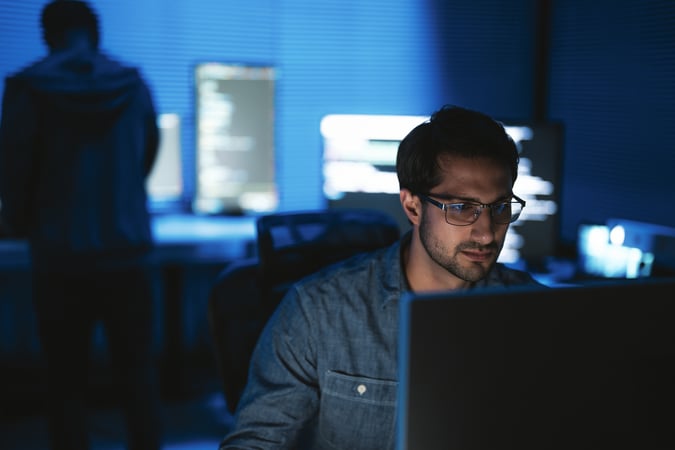 man with glasses looking at a computer monitor