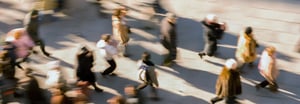 A blurry shot of people in motion as they walk across the street