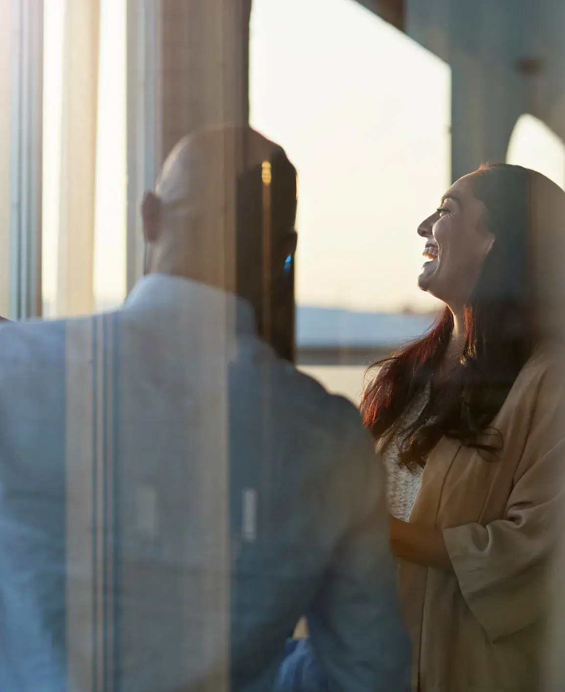 Two colleagues laughing by a window